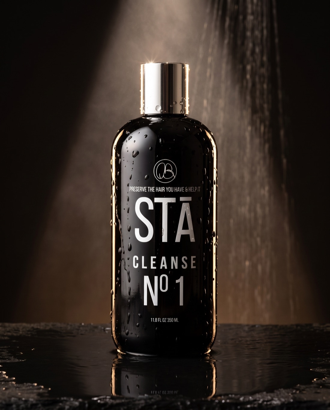 STĀ Cleanse Nº1 purifying cleanser, black bottle with chrome cap, water droplets under spotlight